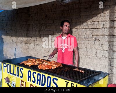 Homme à barbiche mariné poulet grillé qui tend à vendre de l'alimentation de rue en dehors de la cuisson sur gril trottoir Oaxaca Mexique Banque D'Images