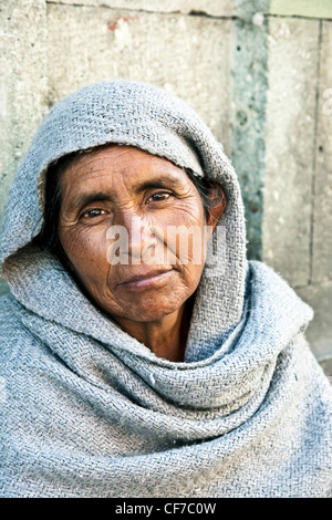 Beau portrait de rue femme mendiant autochtones avec des yeux sombres accroupi contre le mur de pierre en quartier Centro Oaxaca Banque D'Images