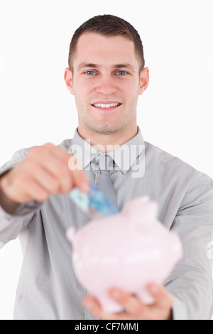 Portrait of a young businessman putting a vingt euros remarque dans une tirelire Banque D'Images