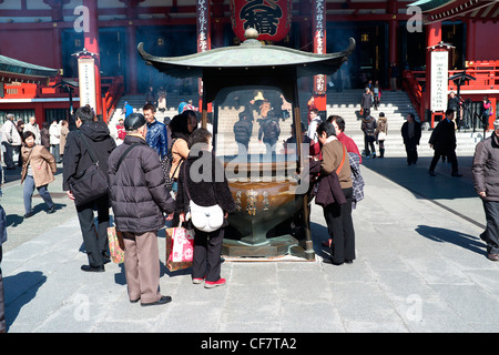 Les dévots et touristiques autour d'un brûleur d'encens au Temple Senso-Ji à Tokyo, Japon Banque D'Images