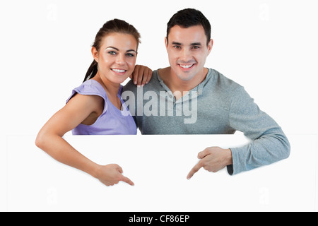 Jeune couple pointing at publicité en dessous d'eux Banque D'Images