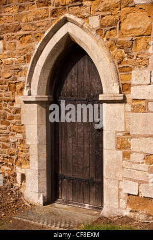 Old Stone a souligné porte arc gothique avec porte en bois, l'église de Saint Swithun, Grand Dalby, Leicestershire, England, UK Banque D'Images