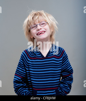 Portrait d'un garçon avec des lunettes montrant ses premières dents de lait manquantes Banque D'Images