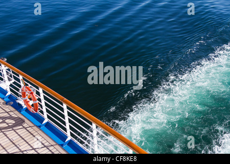 Le balcon d'un navire de croisière avec un modèle d'onde derrière dans l'eau, au coucher du soleil. Banque D'Images