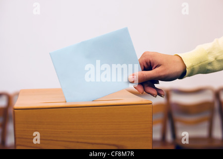 Une jeune femme donne à une élection vote. bulletin de vote au bureau de vote. Banque D'Images