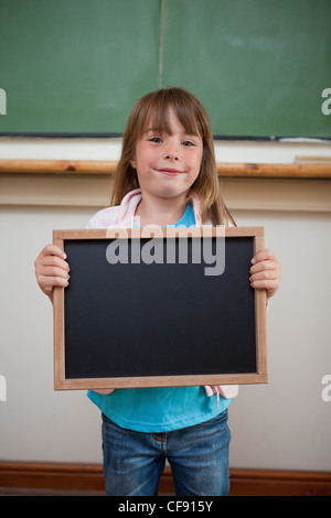 Portrait of a smiling girl holding une ardoise scolaire Banque D'Images