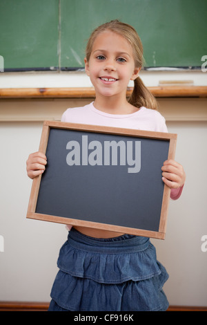 Portrait of a happy girl holding dans une école de l'ardoise Banque D'Images