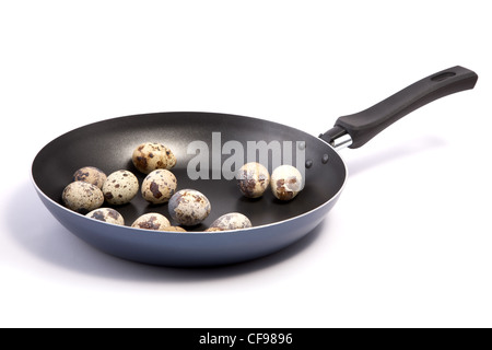 Poêle avec des oeufs de cailles sur fond blanc Banque D'Images