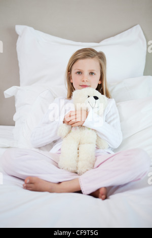 Girl hugging son ours en peluche sur le lit Banque D'Images