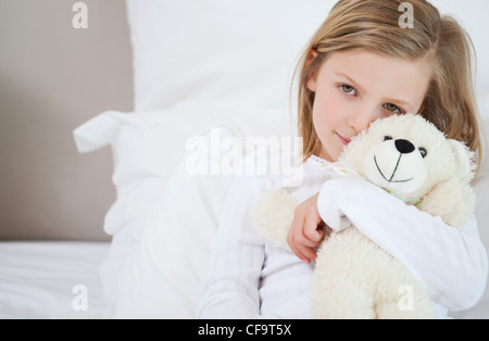 Fille avec son ours en peluche assis sur le lit Banque D'Images