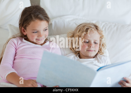 Frère et sœur lecture histoire de temps de lit Banque D'Images