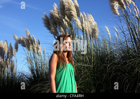 Femme portant des halternecked vert haut, debout en face de certaines grandes pampas grass avec une expression inquiète Banque D'Images