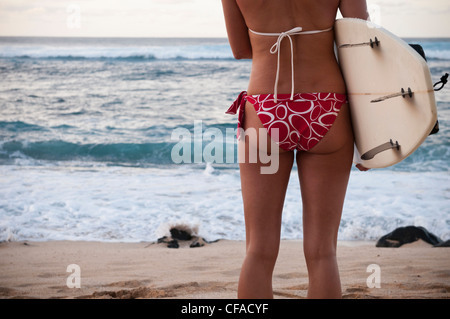 Surfer carrying surfboard on beach Banque D'Images