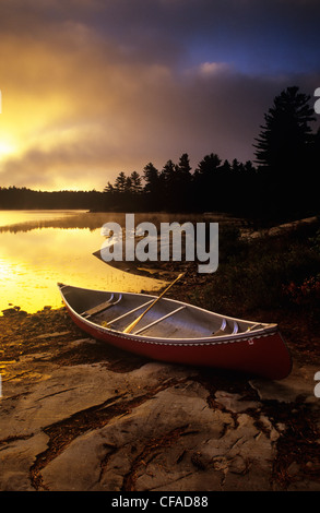 Un canot à terre assis dans un camping, au coucher du soleil, le Parc provincial Killarney, l'Ontario, Canada. Banque D'Images