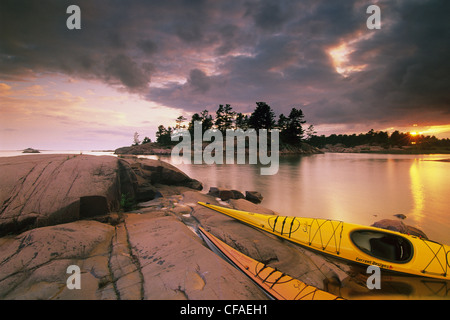 Coucher du soleil, les kayaks sur la plage, le ruisseau Chikanishing, Georgian Bay Killarney Provincial Park, Ontario, Canada. Banque D'Images