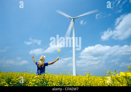 Jeune fille de 15 ans avec visualisation pinwheel wind turbine in champ de canola, près de St Leon, au Manitoba, Canada. Banque D'Images