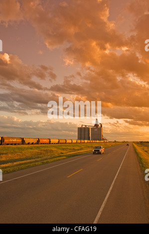 Route à travers les prairies et l'intérieur des terres à grain en arrière-plan, près d'Estevan, Saskatchewan, Canada Banque D'Images