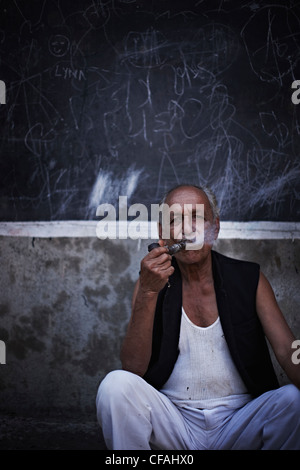 Man smoking pipe on city street Banque D'Images