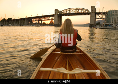 Girl canoë à False Creek, pont Burrard au coucher du soleil, Vancouver, Colombie-Britannique, Canada. Banque D'Images