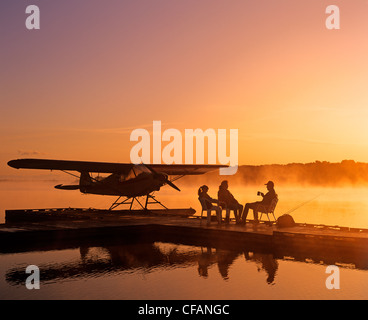 Silhouette of family sitting on dock hydravion le matin, la rivière Rouge, Manitoba, Canada Banque D'Images