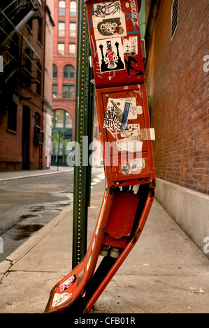 Boîte aux lettres rouge tordues qui fait l'objet d'autocollants et graffiti NYC. Banque D'Images