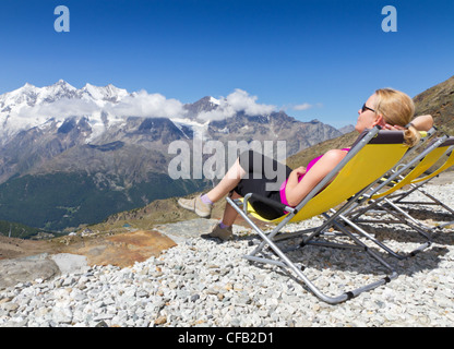 Jeune femme apprécie le soleil et se détend sur une toile président entouré de montagnes enneigées des alpes Saas Fee, Suisse Banque D'Images