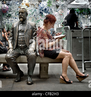 Femme lisant un livre à côté de la statue de Rovira i Trias, un architecte catalan, dans le quartier de Gracia à Barcelone. Banque D'Images