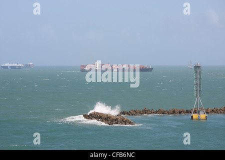 Vagues vagues sur les brise-lames à Colon, Panama, avec les cargos au loin. Banque D'Images