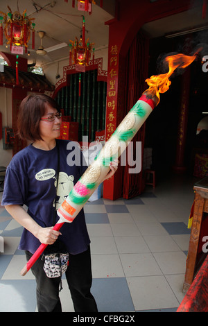 Femme bougie allumée pendant les célébrations du Nouvel An chinois dans le temple pagode à Sibu, Bornéo, Malaisie Banque D'Images