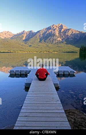 L'âge moyen homme méditant sur dock à Pyramid Lake, Jasper National Park, Alberta, Canada. Banque D'Images