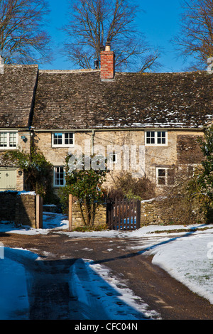 Une rangée de cottages en pierre de Cotswold jolie dans la neige à Ampney Saint Pierre, Gloucestershire, England, UK Banque D'Images