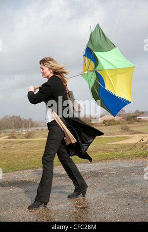 Femme lutte pour garder son parapluie dans un haut vent Banque D'Images