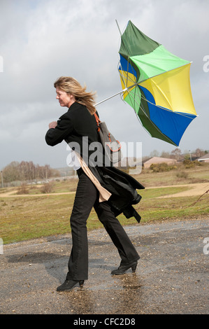 Femme lutte pour garder son parapluie dans un haut vent Banque D'Images