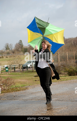 Femme lutte pour garder son parapluie dans un haut vent Banque D'Images