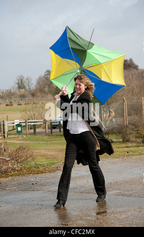 Femme lutte pour garder son parapluie dans un haut vent Banque D'Images