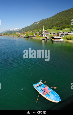 Deux personnes d'un bateau d'aviron sur le lac Weissensee, village Gatschach en arrière-plan, le lac Weissensee, Carinthie, Autriche, Europe Banque D'Images