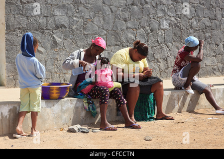 Sal Rei Boa Vista Cap Vert les femmes locales à l'extérieur du marché de poisson municipal avec une mère de donner son bébé Un verre d'eau en bouteille. Banque D'Images