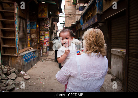 Dame tenant un enfant anglais/Thaï marchant dans une rue secondaire au Caire, Egypte Banque D'Images