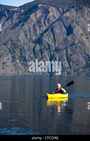 Un homme à la retraite aventureux kayak à travers un immense lac calme dans l'Idaho. Banque D'Images