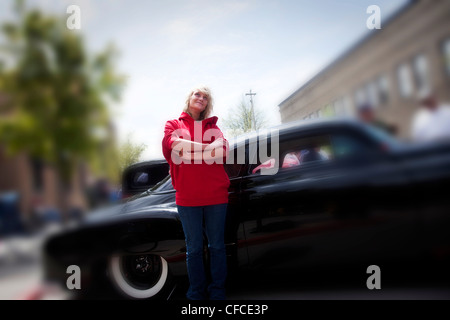 Une belle jeune femme sourit en se tenant debout à côté d'une voiture d'époque dans l'Idaho. Banque D'Images