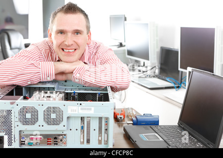 Réparateur avec ordinateur, un propriétaire de petite entreprise. Moniteurs et autres ordinateurs portables dans l'arrière-plan en attente de service. Banque D'Images