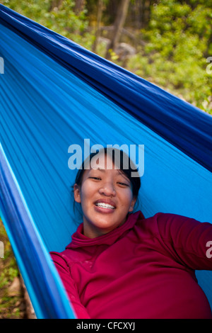 Une jeune femme asiatique se détend dans un hamac tandis que sur un rocher climging voyage dans le parc national Jasper, Alberta, Canada Banque D'Images