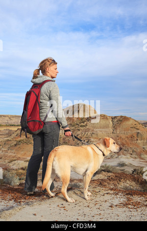 Randonnée femme avec son chien, debout sur un un panorama. Voleur de chevaux Canyon, Drumheller, Alberta, Canada. Banque D'Images