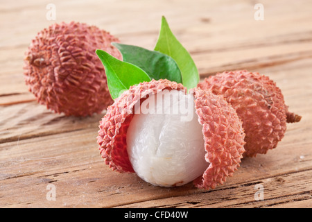 Le litchi avec des feuilles sur une table en bois. Banque D'Images