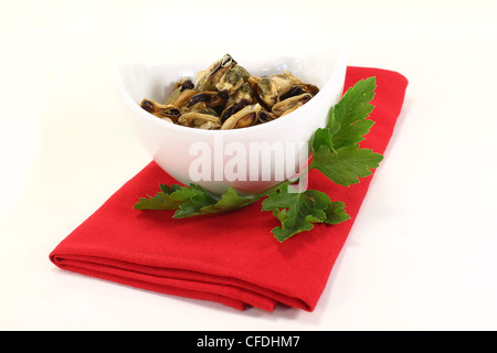 Moules marinées avec persil plat dans un bol sur la serviette rouge Banque D'Images