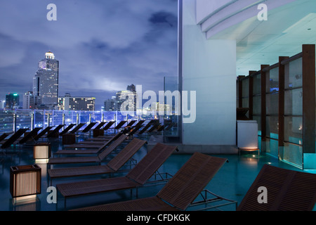 Des chaises longues et une piscine extérieure à la Millennium Hilton Hotel, Bangkok, Thaïlande Banque D'Images