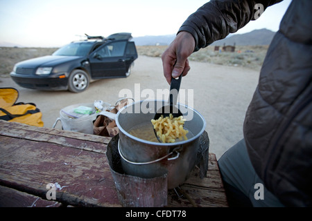 Un homme en train de préparer un repas au camp. Banque D'Images