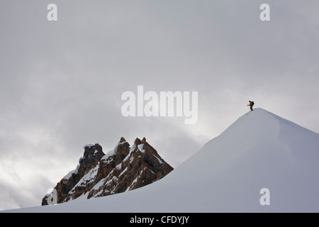 Un seul skieur d'arrière-pays prend dans la vue avant de tomber dans. Cascade Lodge, Golden, Colombie-Britannique, Canada Banque D'Images