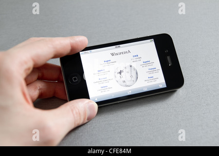 Man main holding Apple iPhone avec Wikipedia page de démarrage sur un écran. Banque D'Images