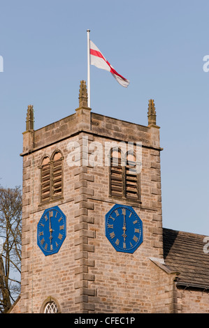 Drapeau flotte haut sur la pittoresque ville de St Peter's Church tower et de l'heure sur les horloges 2 lit 18h00 - soirée de printemps ensoleillé, Addingham village, Yorkshire, Angleterre. Banque D'Images